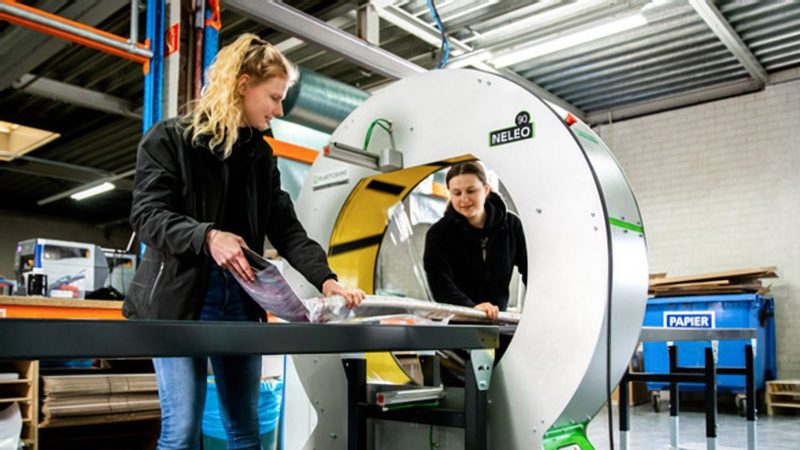 Twee collega's wikkelen een lang pakket in folie